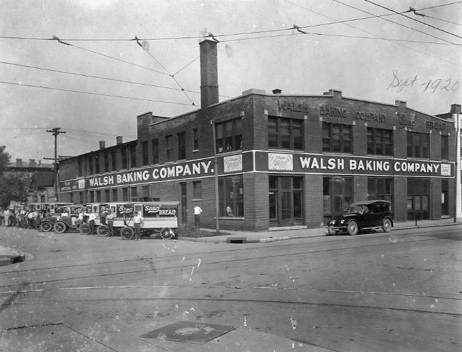 Historic photo of Walsh Baking Company building with delivery trucks outside, circa 1920.