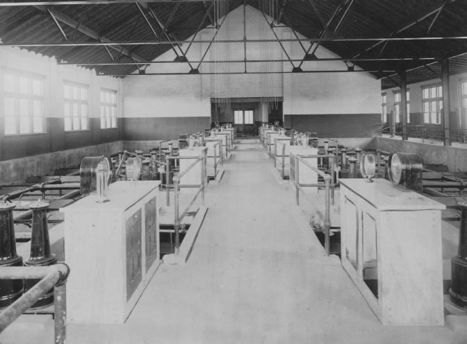 An old industrial room with rows of machinery, possibly a factory or workshop from the early 20th century.