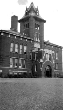 Vintage photo of an old brick building with a tower.