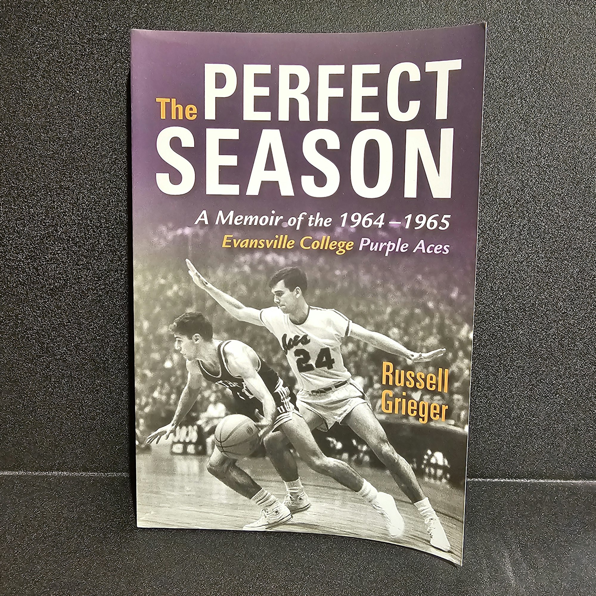 A book titled "The Perfect Season" about Evansville College Purple Aces' 1964-1965 basketball season, with players in action on the cover.