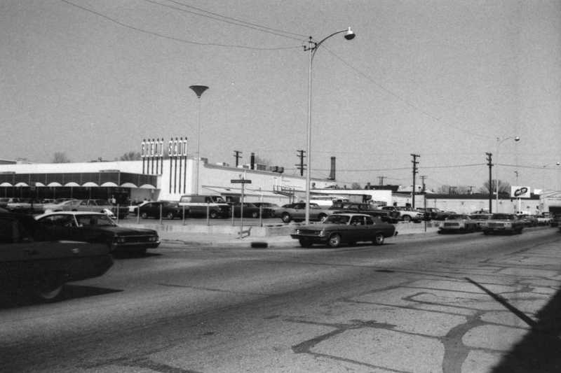 Vintage street scene with cars, buildings, and a sign saying "GOOD FOOD."