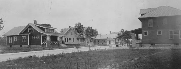Vintage black and white photo of a residential street with houses.