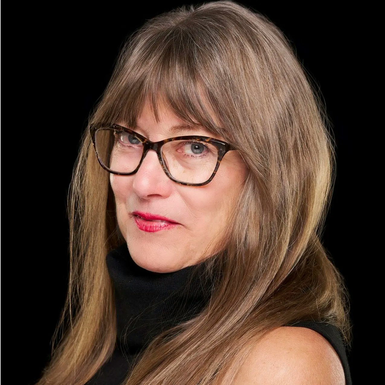 A woman with glasses, long hair, and red lipstick against a black background.