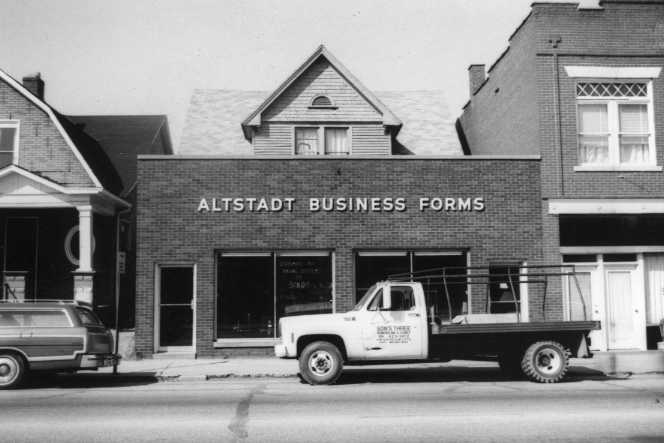 Black-and-white photo of "ALTSTADT BUSINESS FORMS" building with a parked pickup truck.