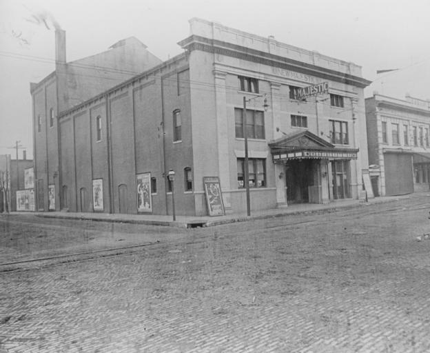 Old photo of a street corner with the Majestic theater and vintage posters.