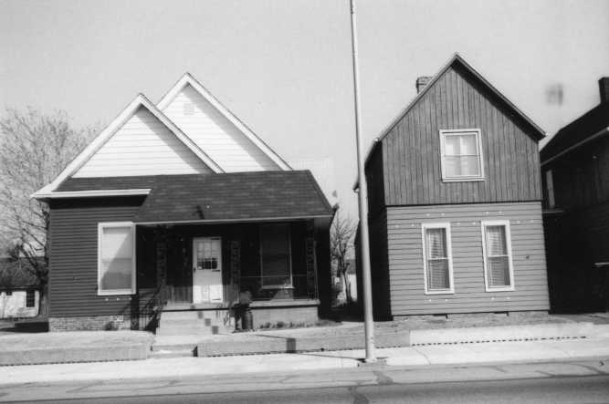 Two adjacent houses with contrasting architecture and a streetlamp, in black and white.
