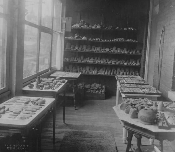 A vintage photo of a bakery with bread and pastries on shelves and tables.