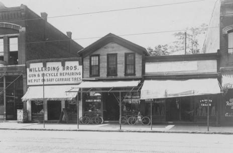 Vintage street view showing "Willerding Bros. Gun & Cycle Repairing" shop with bicycles displayed out front.
