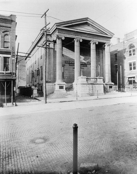 Old neoclassical building with columns, labeled "Old State National Bank," cobblestone street, vintage photo.