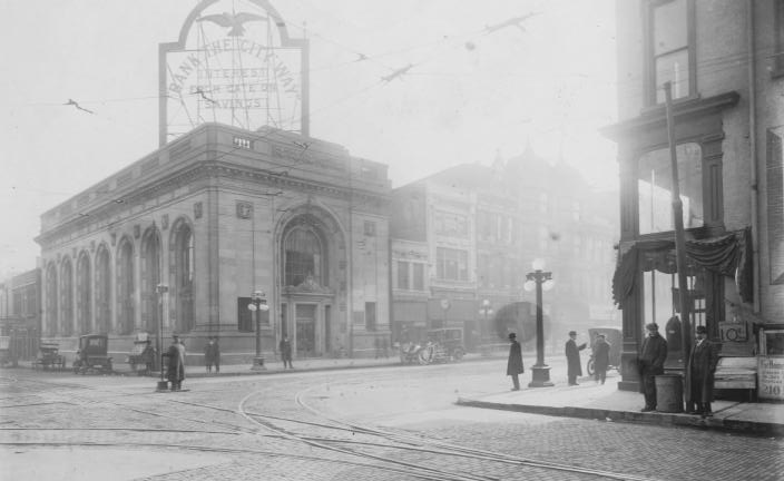 Vintage street scene with a tram, classic architecture, and several people.