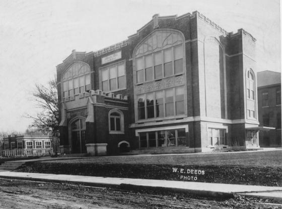Historic two-story building with large windows and a caption by W. E. Deeds. No people visible.