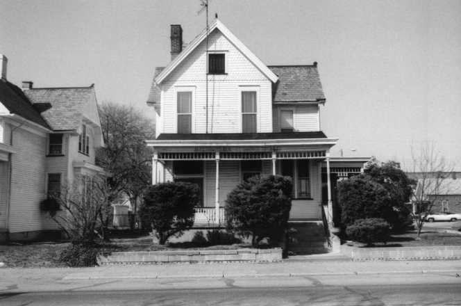 Black and white photo of a traditional two-story house with a front porch.