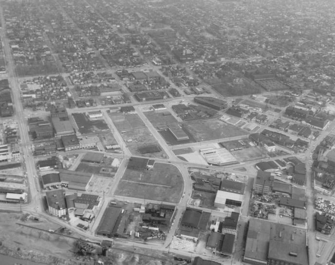 Aerial view of an industrial area with buildings, roads, and surrounding residential blocks.