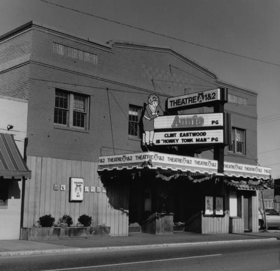A black-and-white photo of an old movie theater marquee advertising a PG movie with an animated character on the sign.