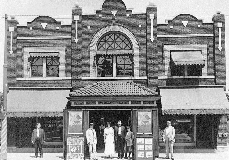 Historic photo of people outside a theater with vintage storefronts.