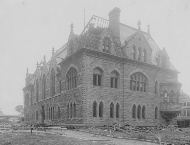 Historic stone building under construction, Gothic architecture, wooden scaffolding, incomplete roof, no people visible.