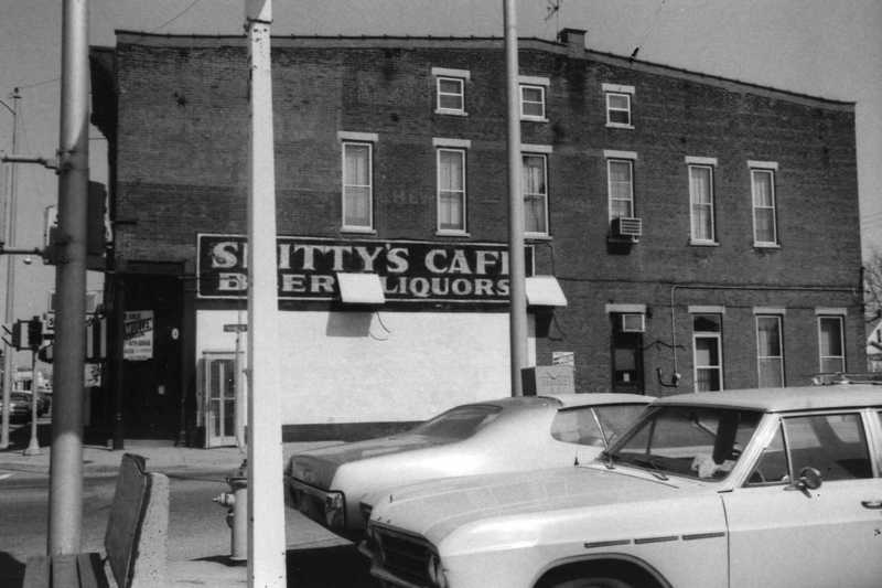 Vintage photo of an old building labeled "Smitty's Café" with parked cars.