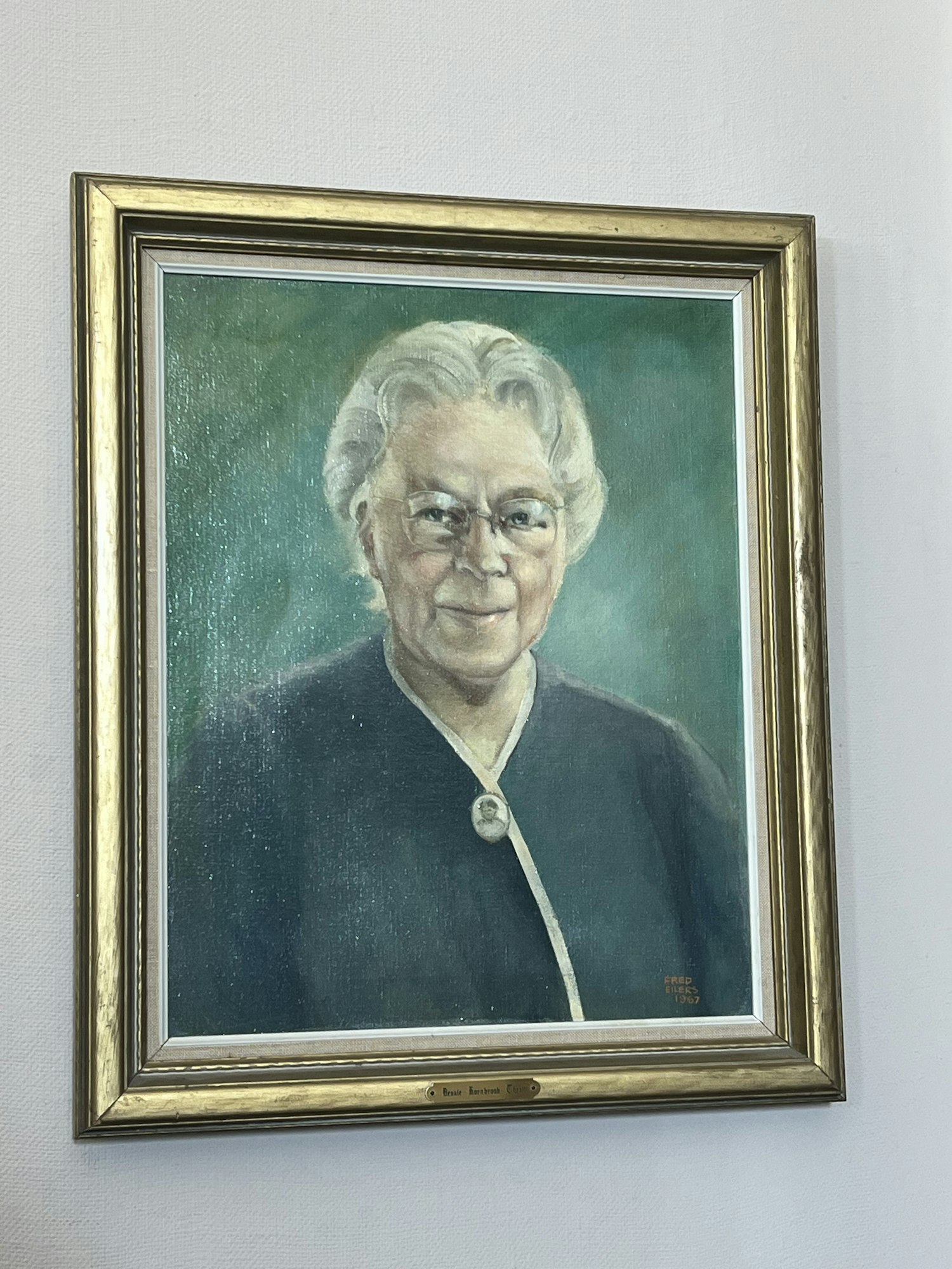 A framed portrait painting of a person with white hair, set against a green background.