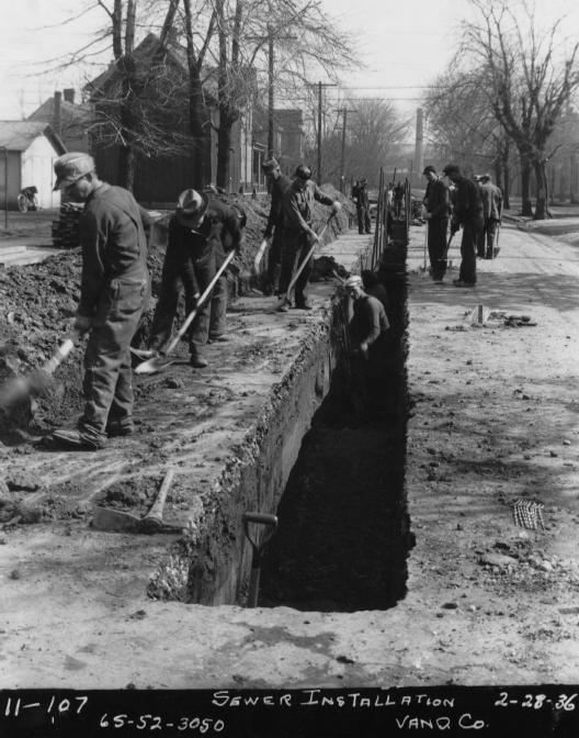 Men working on sewer installation in a trench on a street (dated Feb 28, 1936).