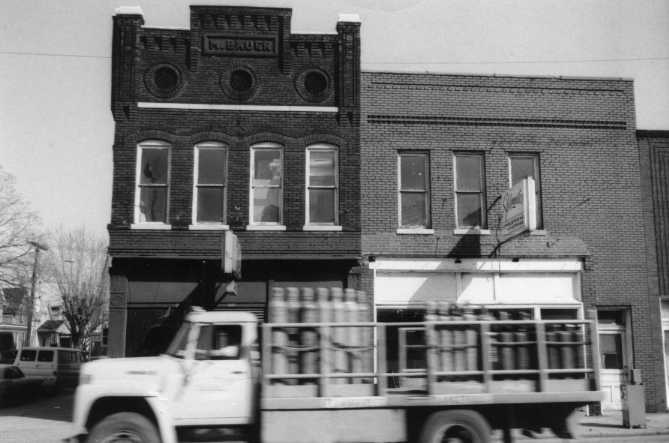 Old brick buildings with a vintage truck passing by.