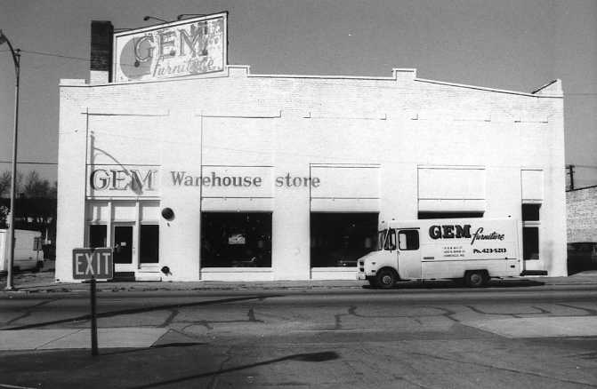A GEM warehouse store with a delivery truck parked outside.