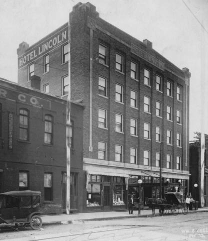 Historic photo of Hotel Lincoln with vintage cars on street.