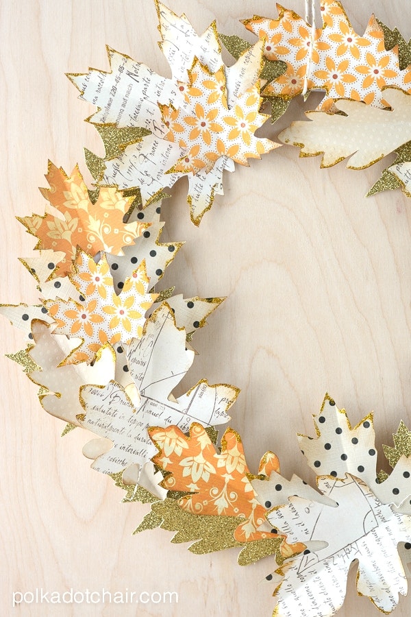Crafted paper leaves with various patterns, some with glitter, arranged in a pile.