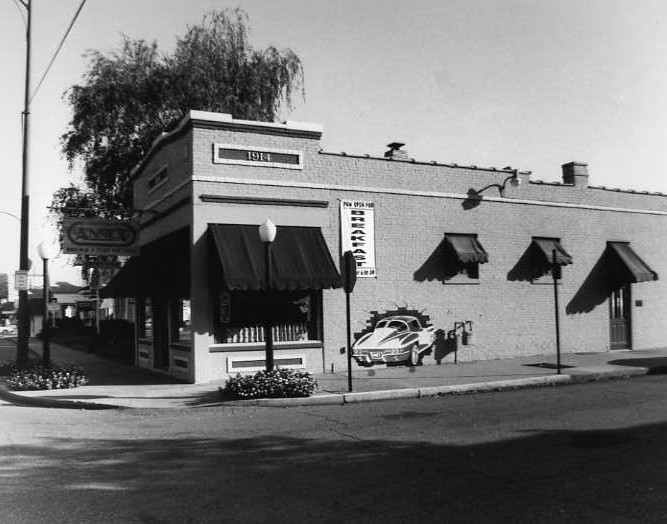 A vintage black and white photo of a corner building with awnings, possibly a shop or diner.