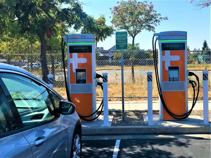 The image shows two electric vehicle charging stations with a nearby sign indicating "Electric Vehicle Charging Only."