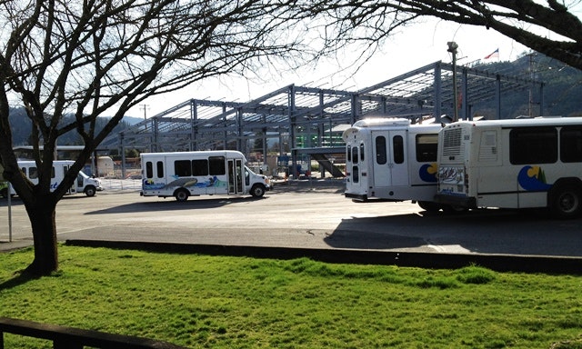 Contains: van, vehicle, transportation, bus, building construction, trees and grass