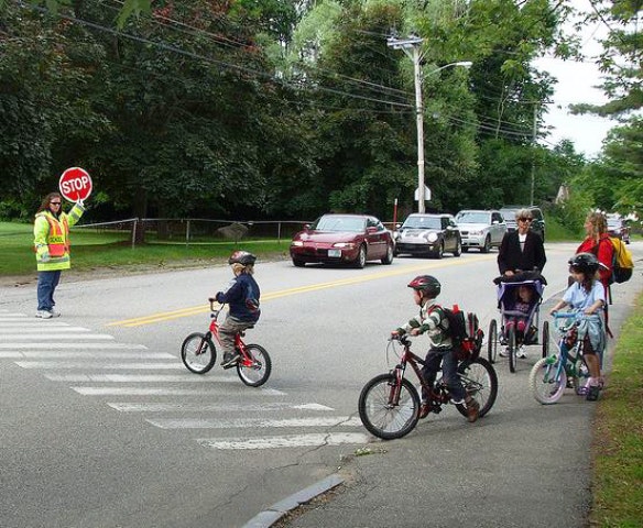 School children on bikes with crossing guard