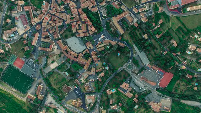 Aerial view of a small town featuring roads, buildings, green spaces, and a soccer field.