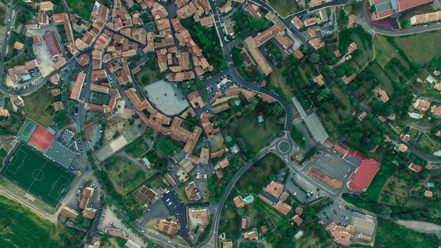 Aerial view of a small town featuring roads, buildings, green spaces, and a soccer field.