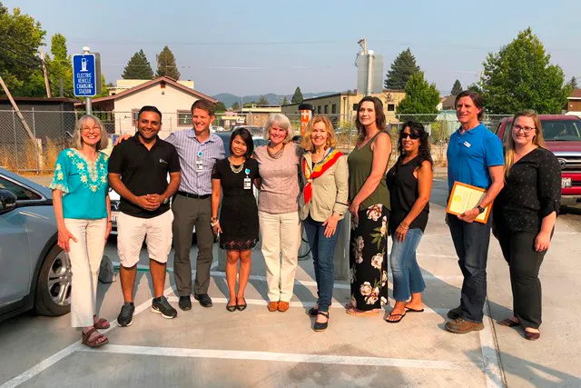 A diverse group of people poses together outdoors, likely at a community event or celebration.