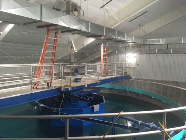 An industrial water treatment facility with circular tanks and catwalks.