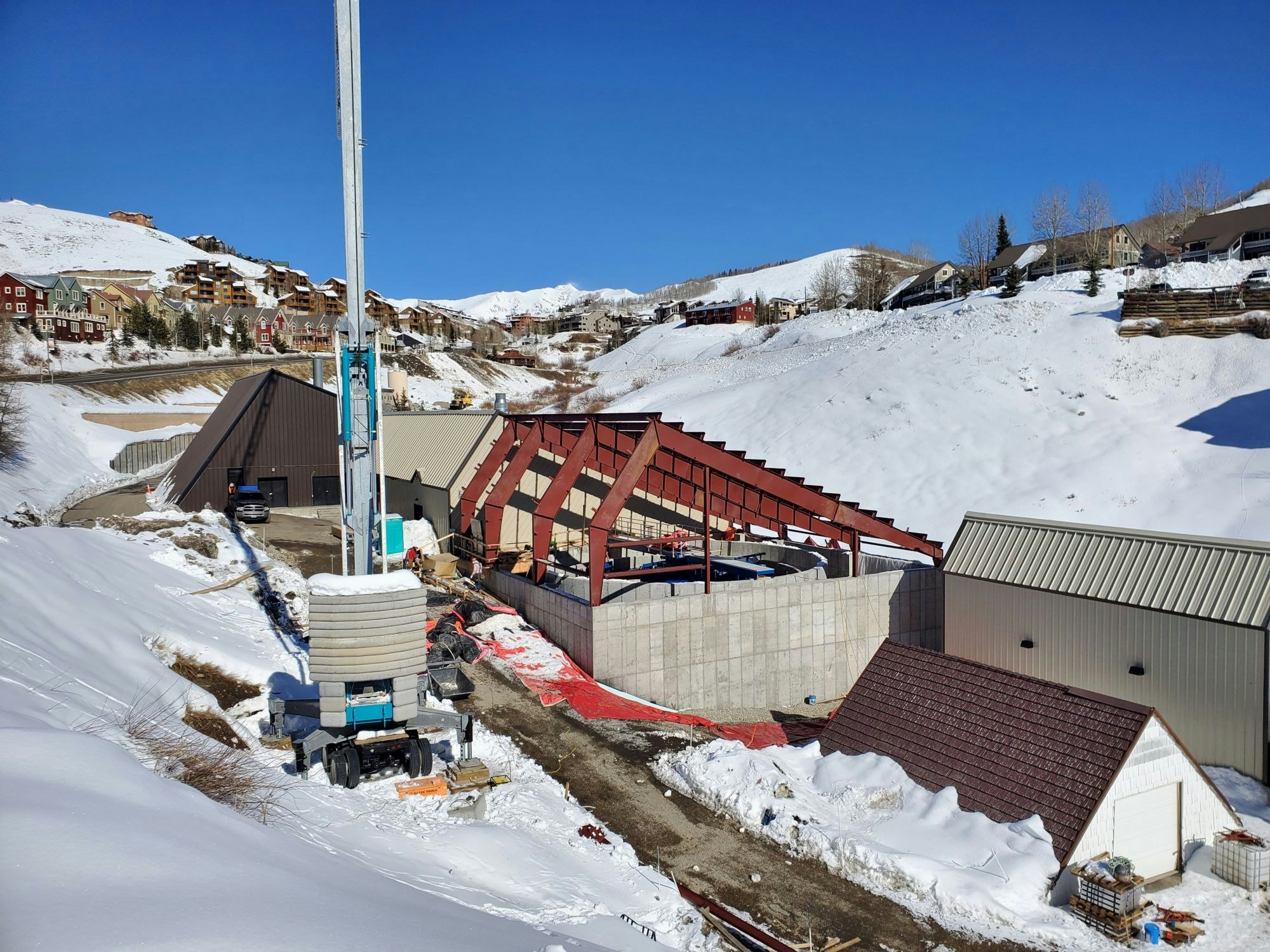 Construction site with crane and buildings amidst a snowy landscape.