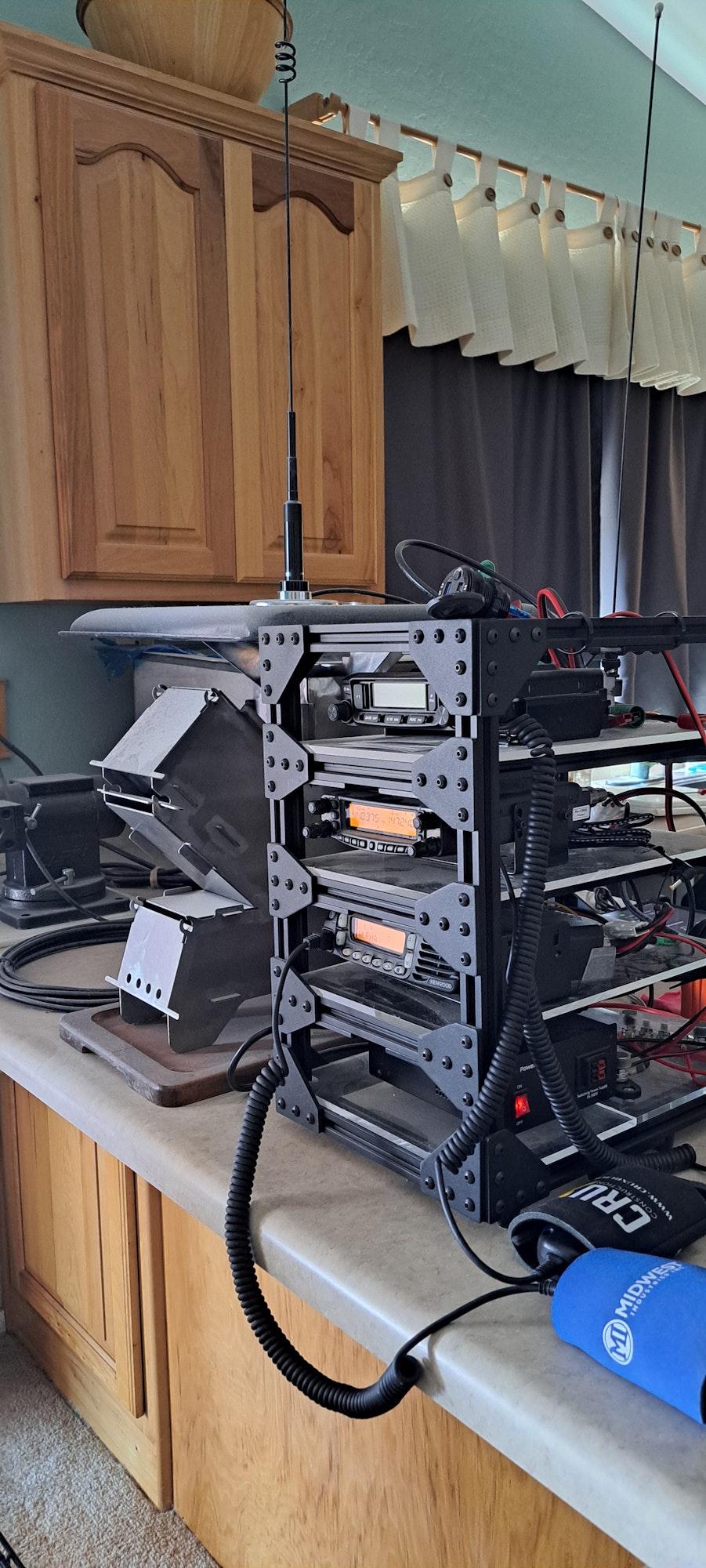 A modular rack with radio equipment and microphones, cables connected, set on a kitchen counter.