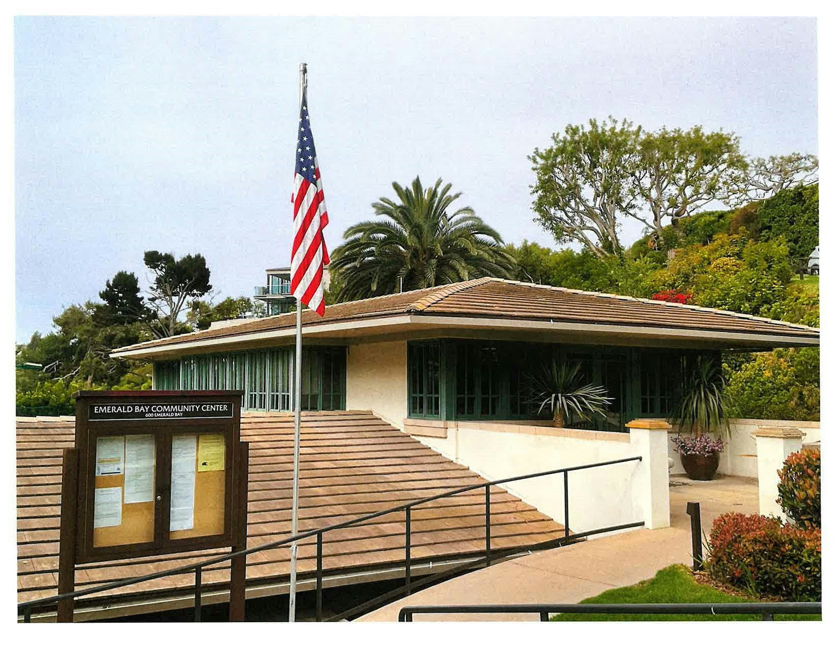 Emerald Bay Community Center with an American flag and a bulletin board. Surrounding greenery and trees are visible.