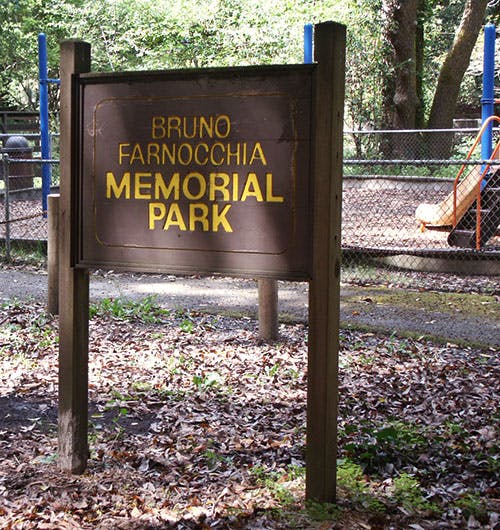 The image features a sign for "Bruno Farnocchia Memorial Park," surrounded by trees and fallen leaves.