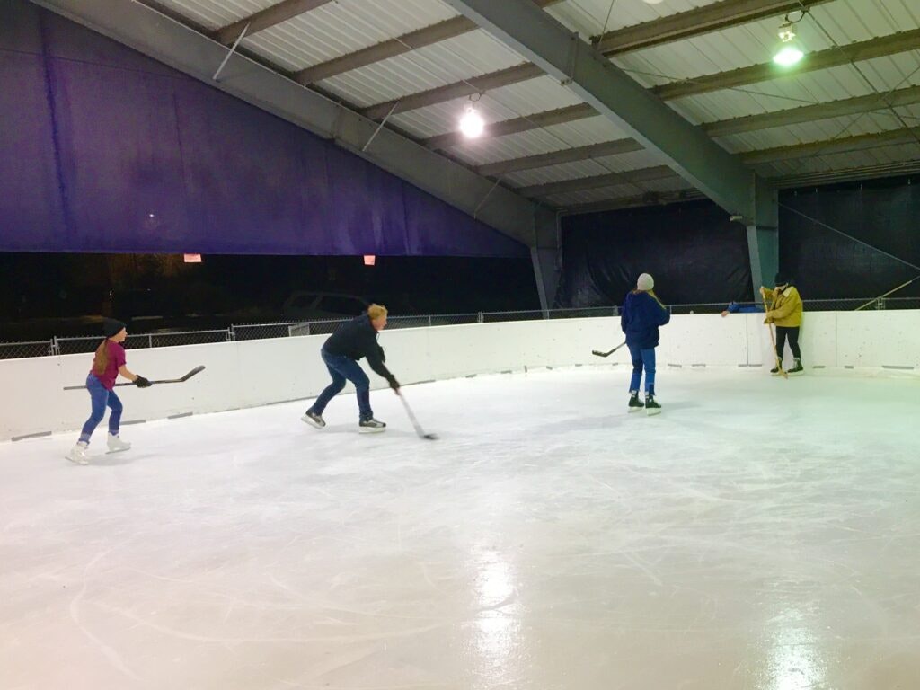 People playing hockey on an indoor ice rink.
