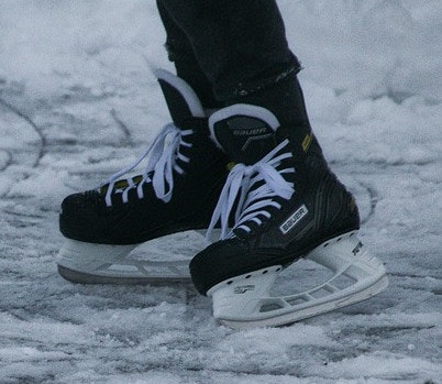 A pair of black hockey skates on ice.