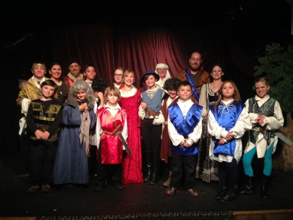 A group of people in medieval-style costumes posing on a stage.