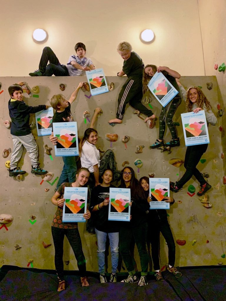 A group of people on a climbing wall holding colorful posters.