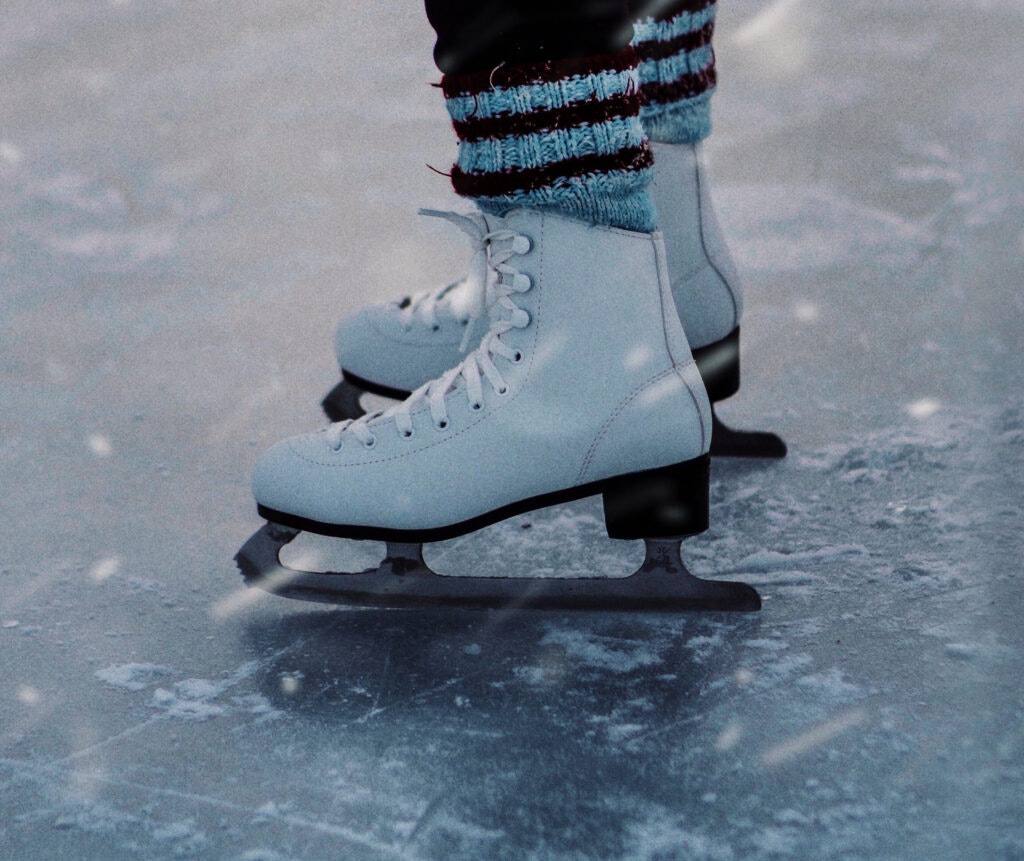 Close-up of white ice skates on a person skating on ice.