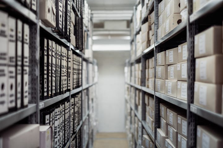 The image shows a storage area filled with organized shelves of boxes and files, likely for archival purposes.