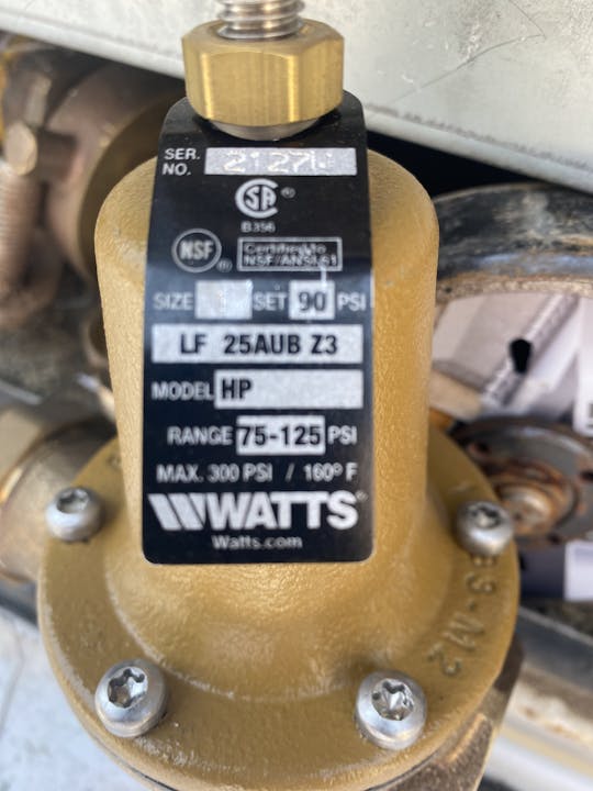 Close-up of a Watts pressure regulator for water, model LF 25AUB Z3, set at 90 PSI.