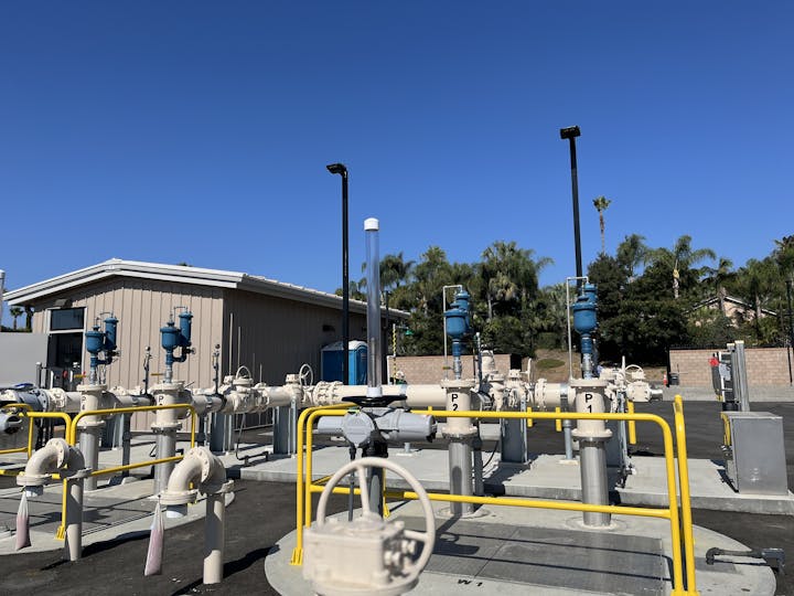 Industrial facility with pipes and valves under a clear blue sky.