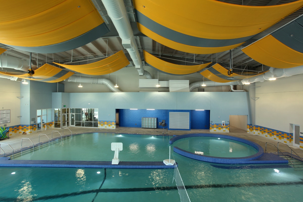 An indoor swimming pool with colorful ceiling baffles, a whirlpool, and lanes for laps.
