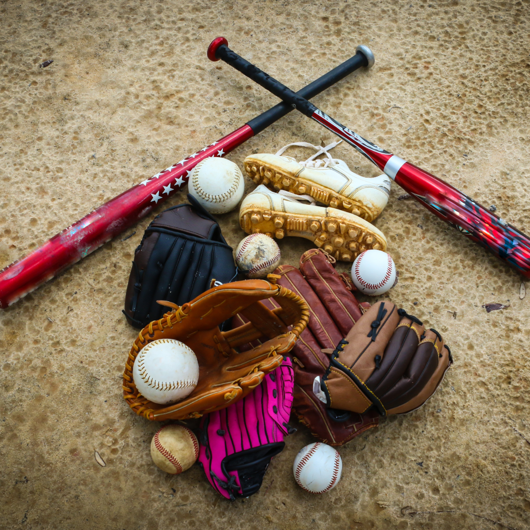 Baseball gear: two bats, five gloves, cleats, and several baseballs on the ground.