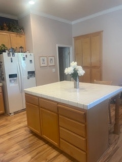 A kitchen with wooden cabinets, a central island with a vase of flowers, and a white refrigerator.